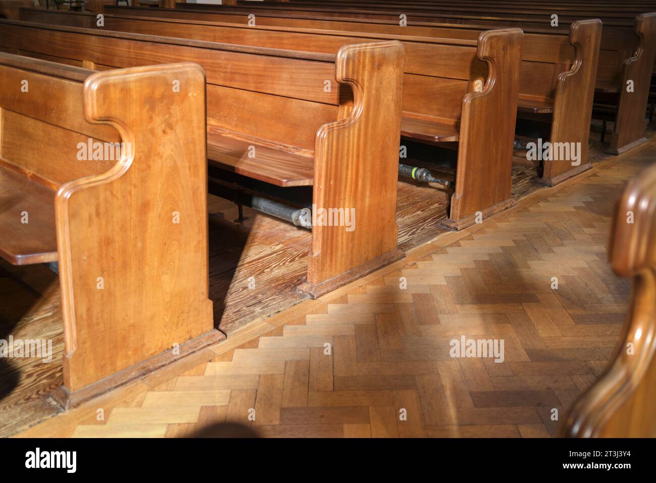 Tubi del poggiapiedi per riscaldamento centrale sotto i petti dei sedili nella Metropolitan Cathedral Church di St David Cardiff Galles del Sud Regno Unito Foto Stock