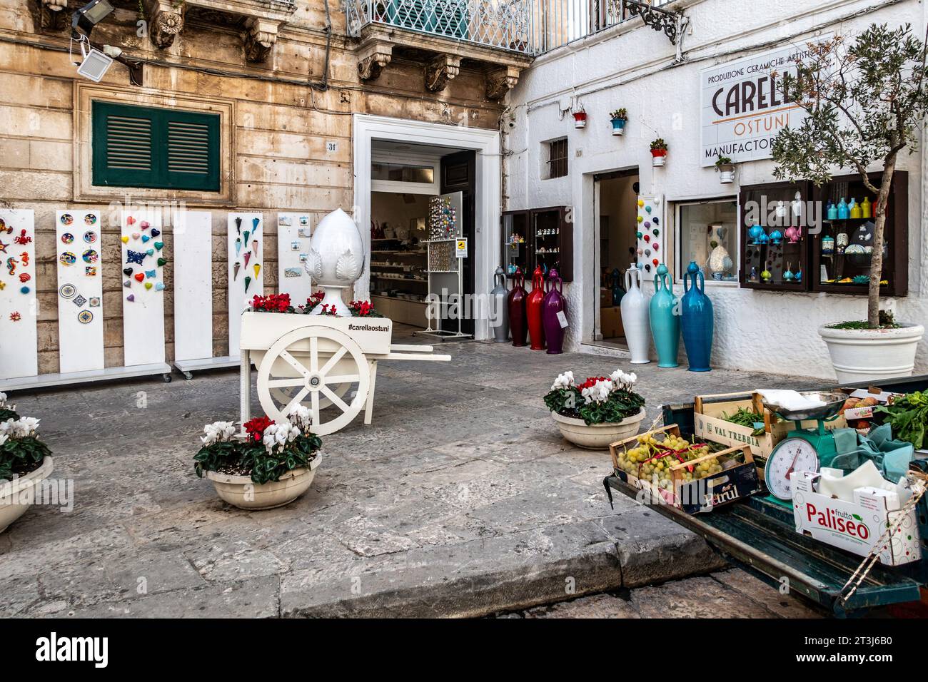 Una selezione di frutta e verdura in vendita all'esterno di un negozio che vende una collezione di ceramiche colorate a Ostuni, Otaly. Foto Stock