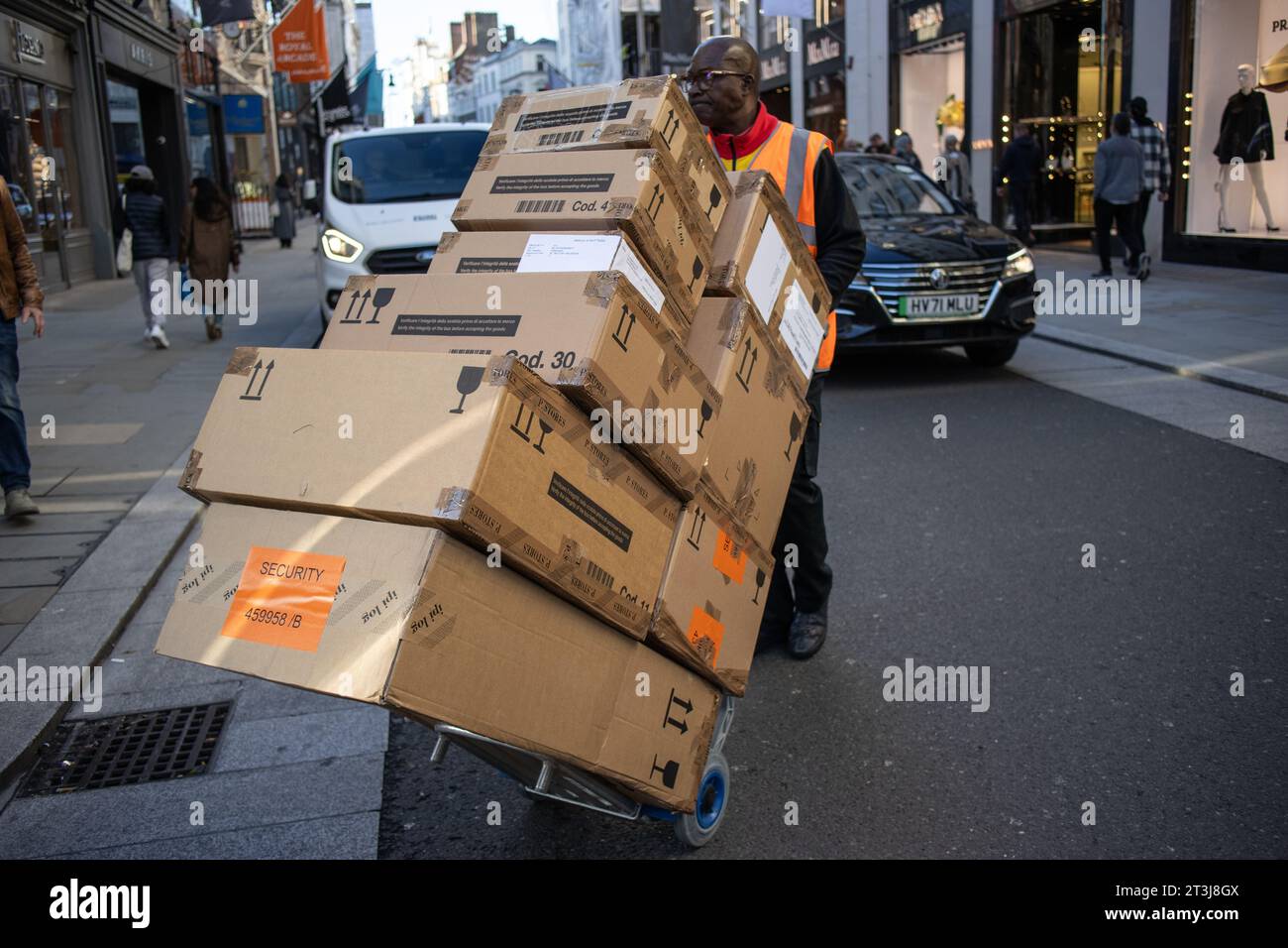 L'addetto alla consegna della Royal mail deve trasportare grandi pacchi lungo Old Bond Street, Mayfair, Londra, Inghilterra, Regno Unito Foto Stock