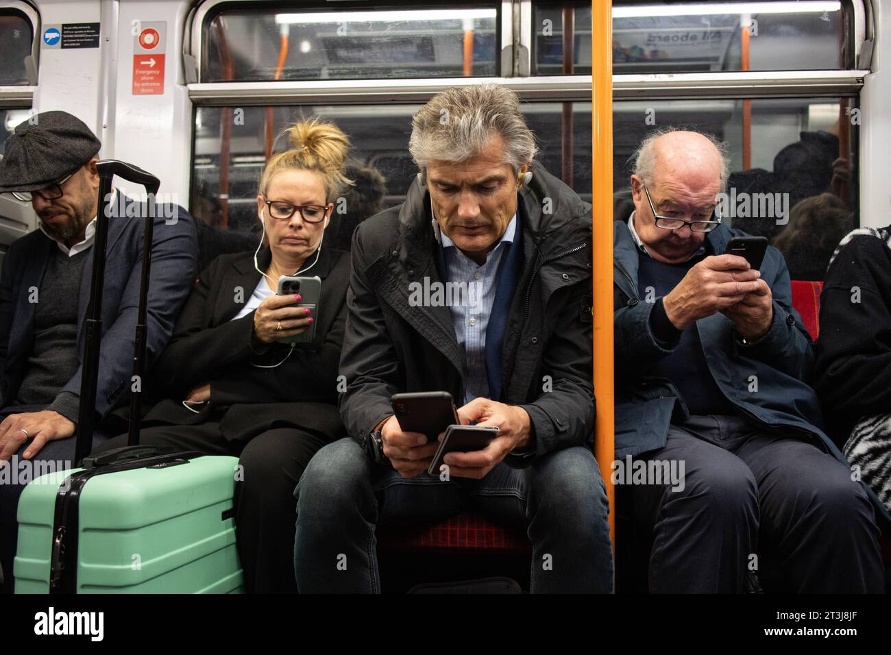 I pendolari della South Western Rail si arrampicavano sui posti a sedere che navigavano sui loro smartphone durante l'ora di punta su un treno dalla stazione principale di Waterloo di Londra. Foto Stock