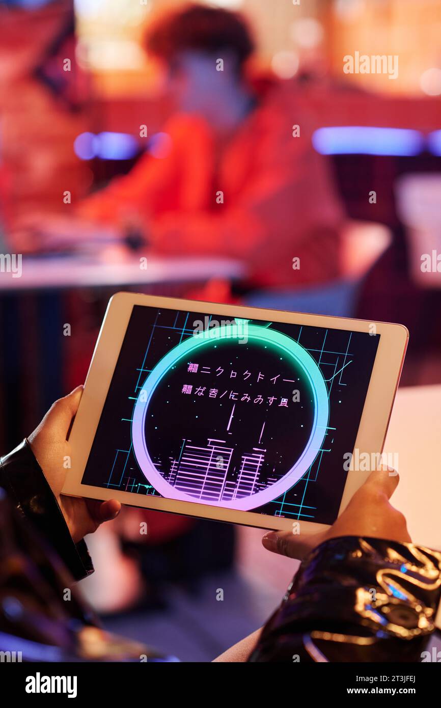 Gruppo di geroglifici senza significato sullo schermo di un tablet tenuto da una ragazza cyberpunk che trascorre del tempo libero in un bar o un bar cyberpunk Foto Stock