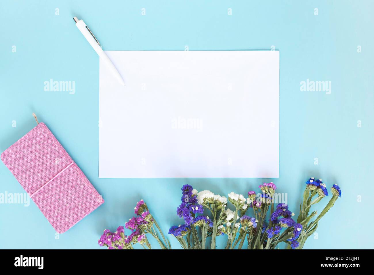 Foglio di carta bianco penna diario mazzo di fiori sfondo blu Foto Stock