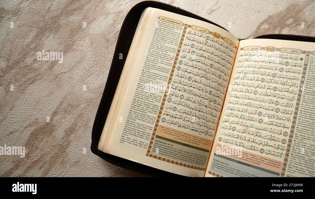 La mano dell'uomo apre la pagina del Corano su sfondo nero. Il Corano è il libro sacro dell'Islam per i musulmani. Foto Stock