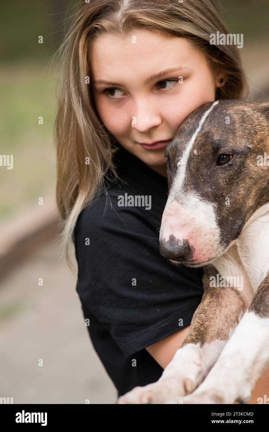 Ritratto di donna caucasica che abbraccia il suo cane Bull terrier all'aperto. Foto Stock