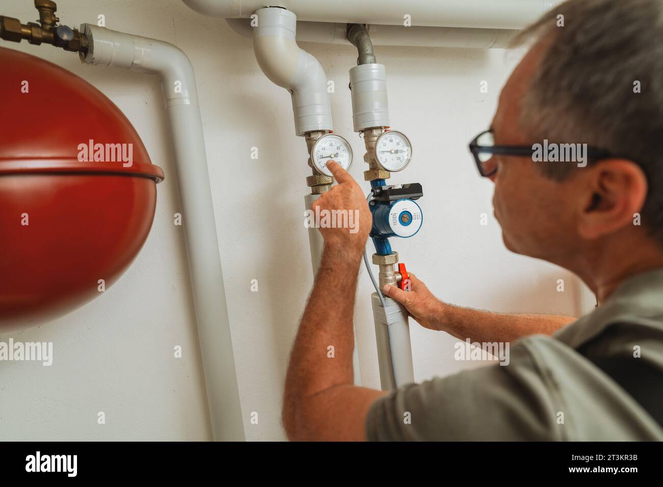 Il tecnico del riscaldamento controlla il termostato a gas in una sala caldaia con un vecchio sistema di riscaldamento a gas. Immagine del concetto di obbligo di sostituzione del riscaldatore a gas Foto Stock