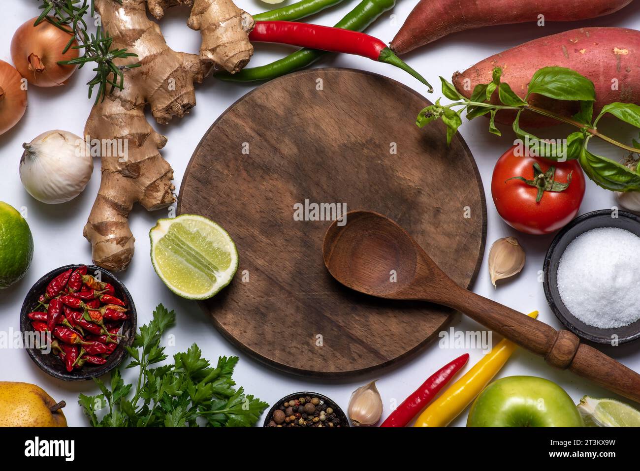 Sfondo composto da ingredienti da cucina. Tagliere in legno e cucchiaio in legno, verdure e spezie varie Foto Stock