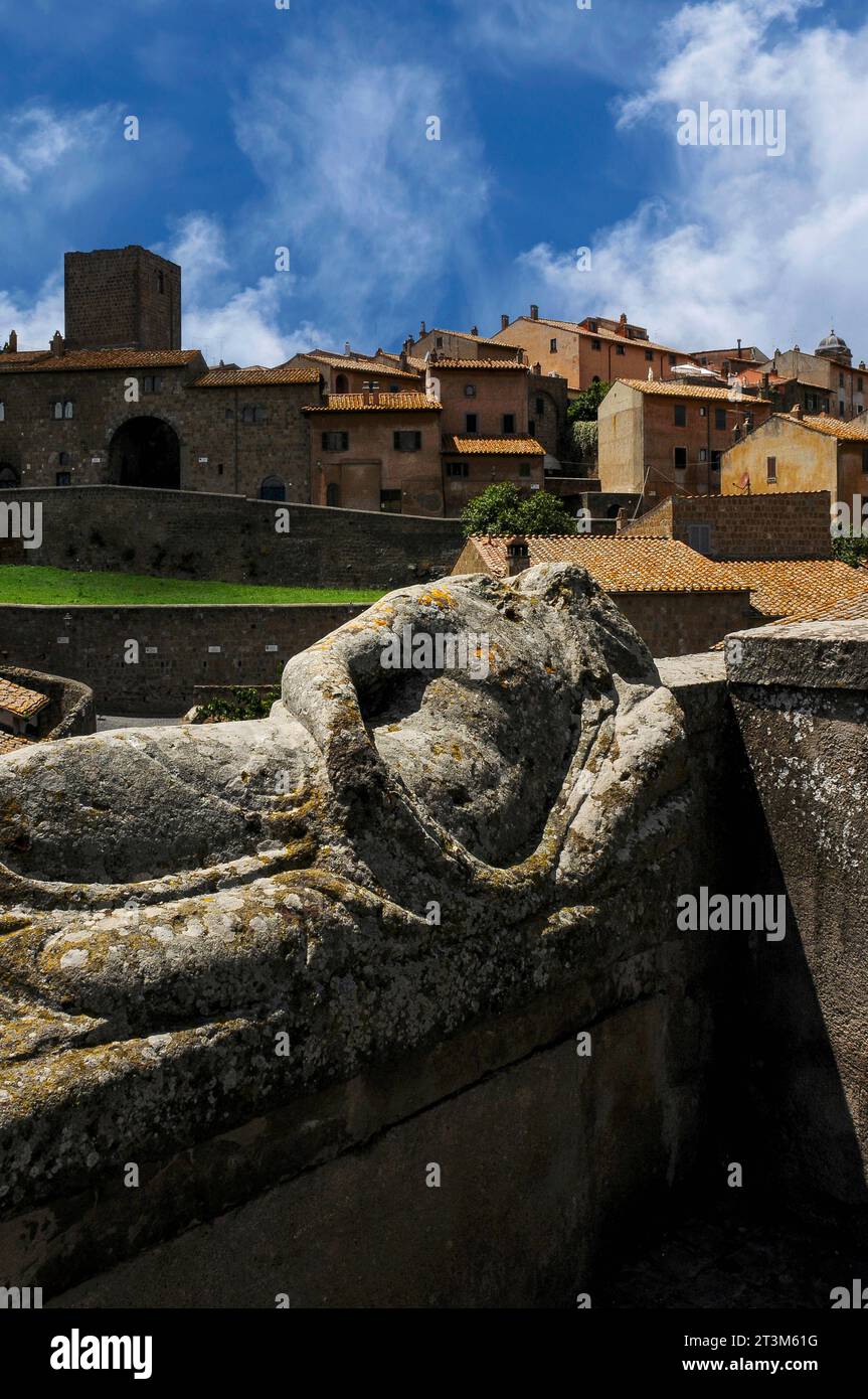 Effigie senza testa che si sdraia sul coperchio dell'antico sarcofago etrusco a Tuscania, Lazio, Italia, con il centro storico di Tuscania alle spalle. Tuscania era un tempo l'antica città etrusca di Tuscana. Si trova a circa 80 km (50 miglia) a nord-ovest di Roma. Foto Stock