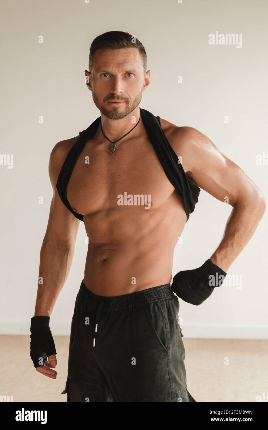 Un uomo muscoloso adulto con un torso nudo si trova in una stanza su uno sfondo chiaro. Foto Stock