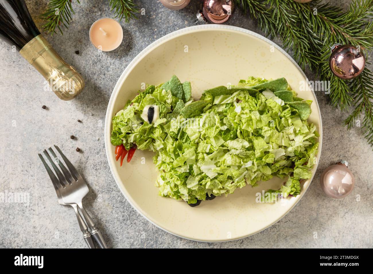 Nuovo 2024 - l'anno di un drago verde, design creativo per le feste. Insalata a strati con funghi, fagioli e cavolo сhinese a forma di drago come simbolo Foto Stock