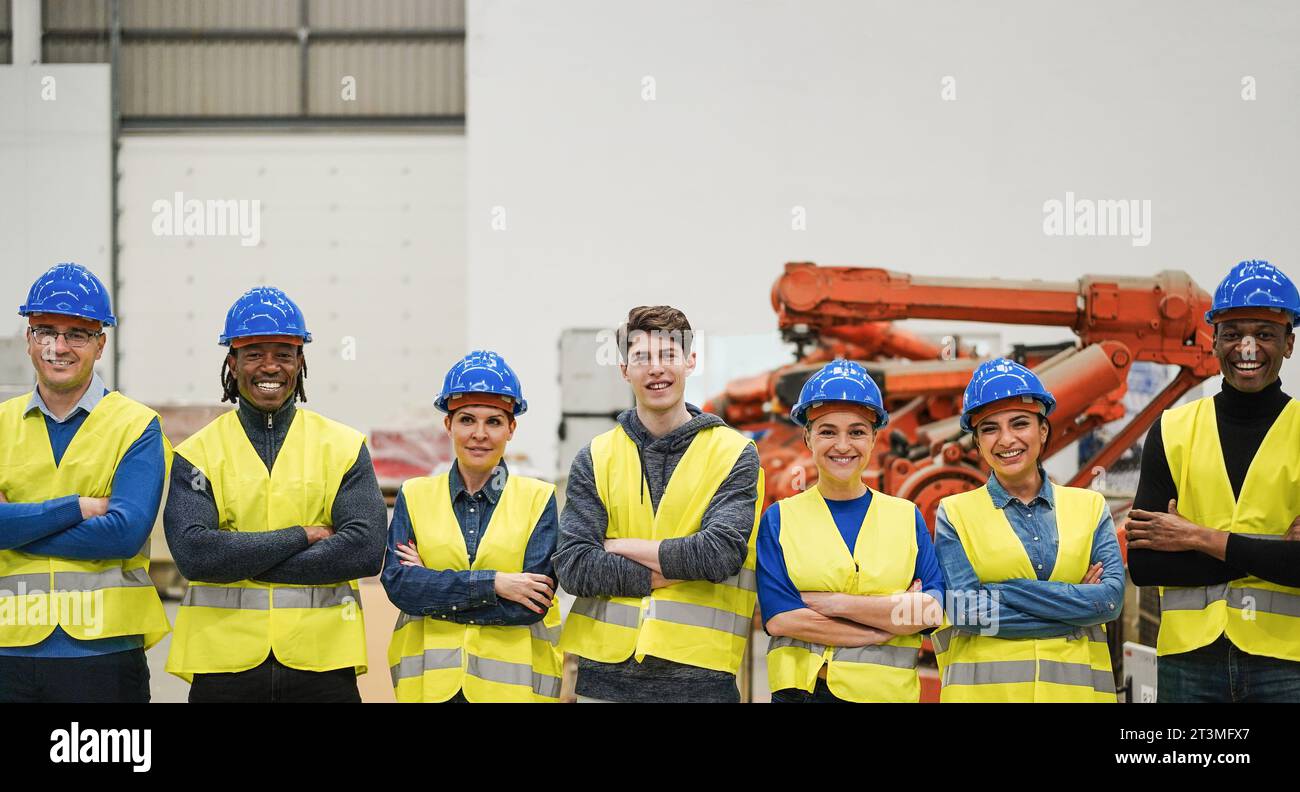 Lavoratori multirazziali all'interno di una fabbrica robotica - uomini e donne al lavoro e concetto di diversità - concentrati sul volto del ragazzo centrale Foto Stock