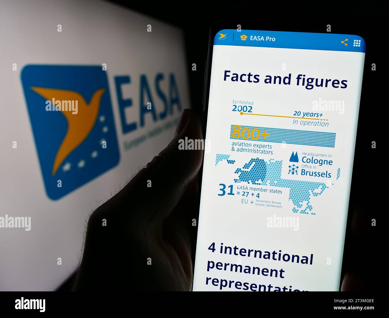 Persona che possiede uno smartphone con il sito web dell’Agenzia dell’Unione europea per la sicurezza aerea (AESA) davanti al logo. Concentrarsi sul centro del display del telefono. Foto Stock