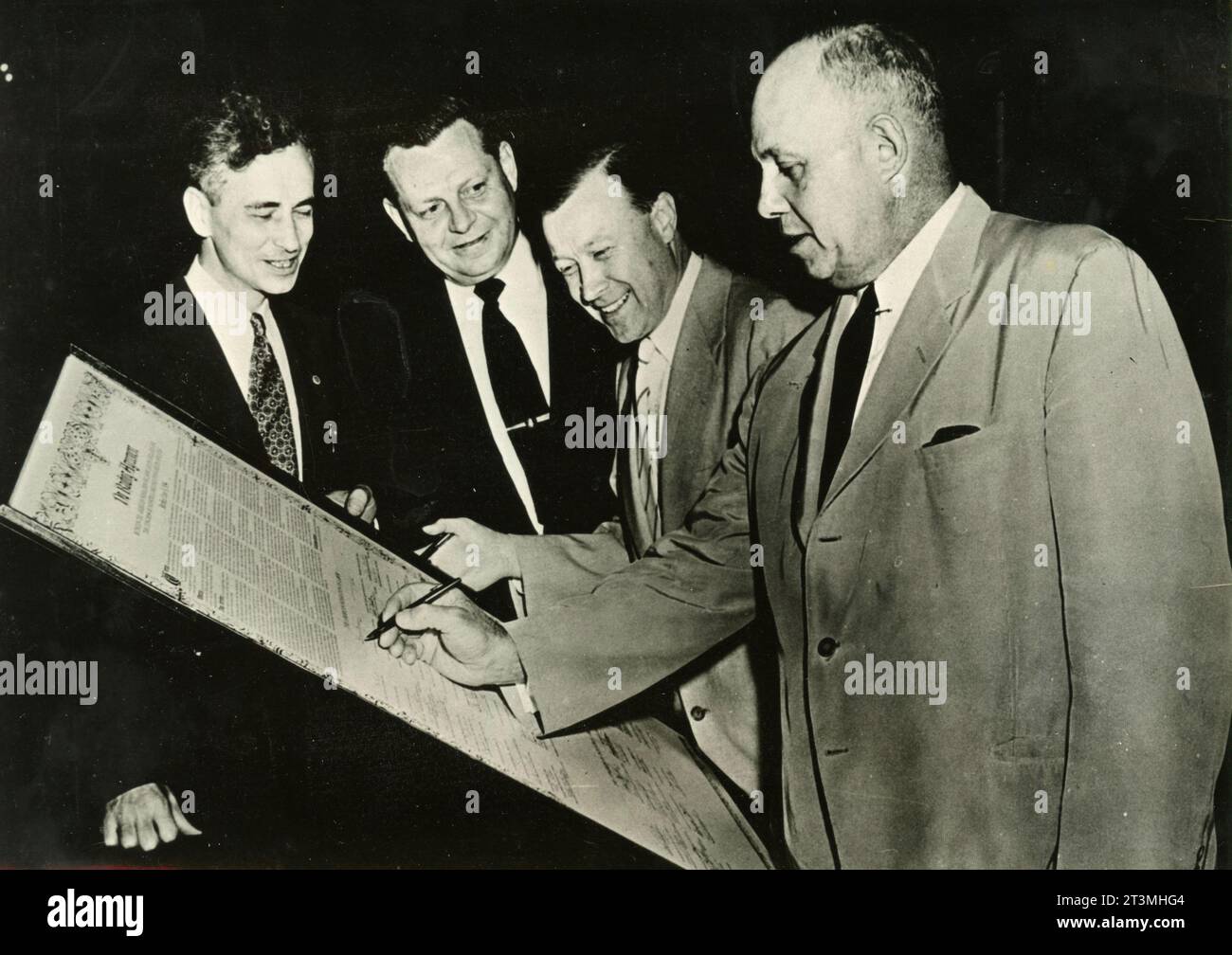 Il presidente della American Federation of Labor Georges Meany firma la storica union of AFL e CIO, mentre Walter Reuther, James Caroy e William Schmitzler guardano, USA 1955 Foto Stock