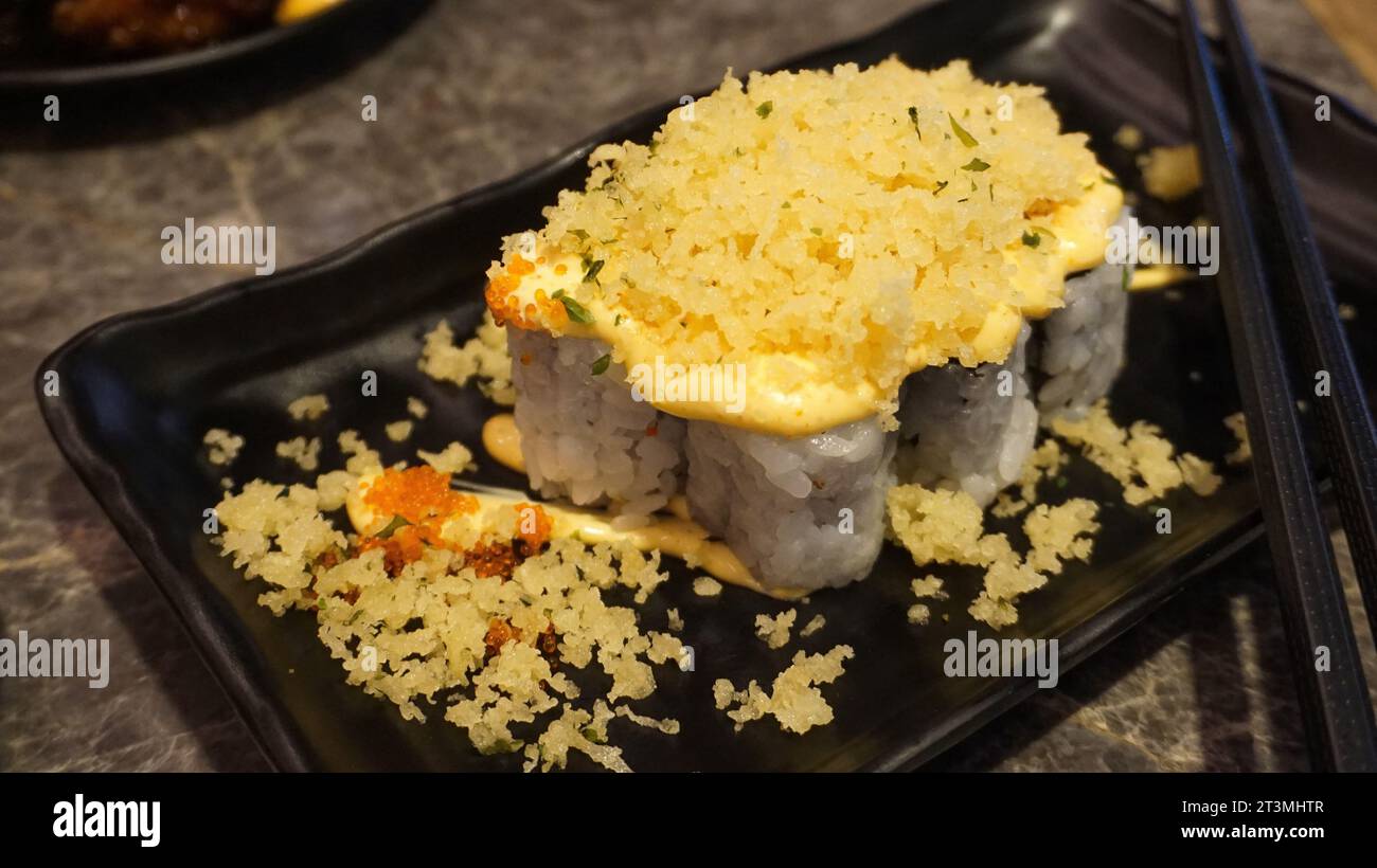 Il sushi è un tipico cibo giapponese contenente riso condito con maionese, farina croccante e una spolverata di uova di pesce Foto Stock