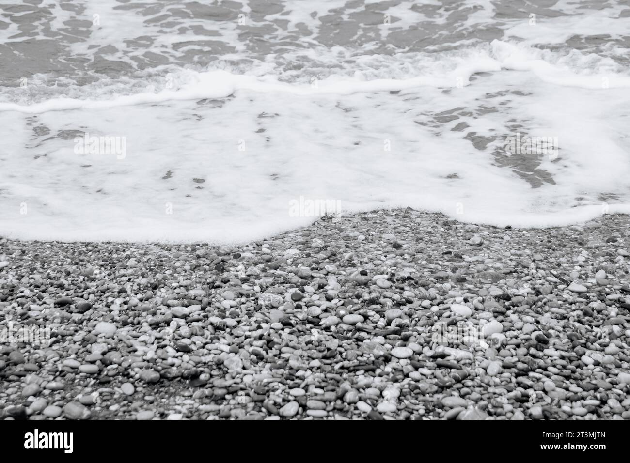 Acqua limpida che si riversa sulla spiaggia di Paralia Ixia al largo della città di Rodi in bianco e nero Foto Stock