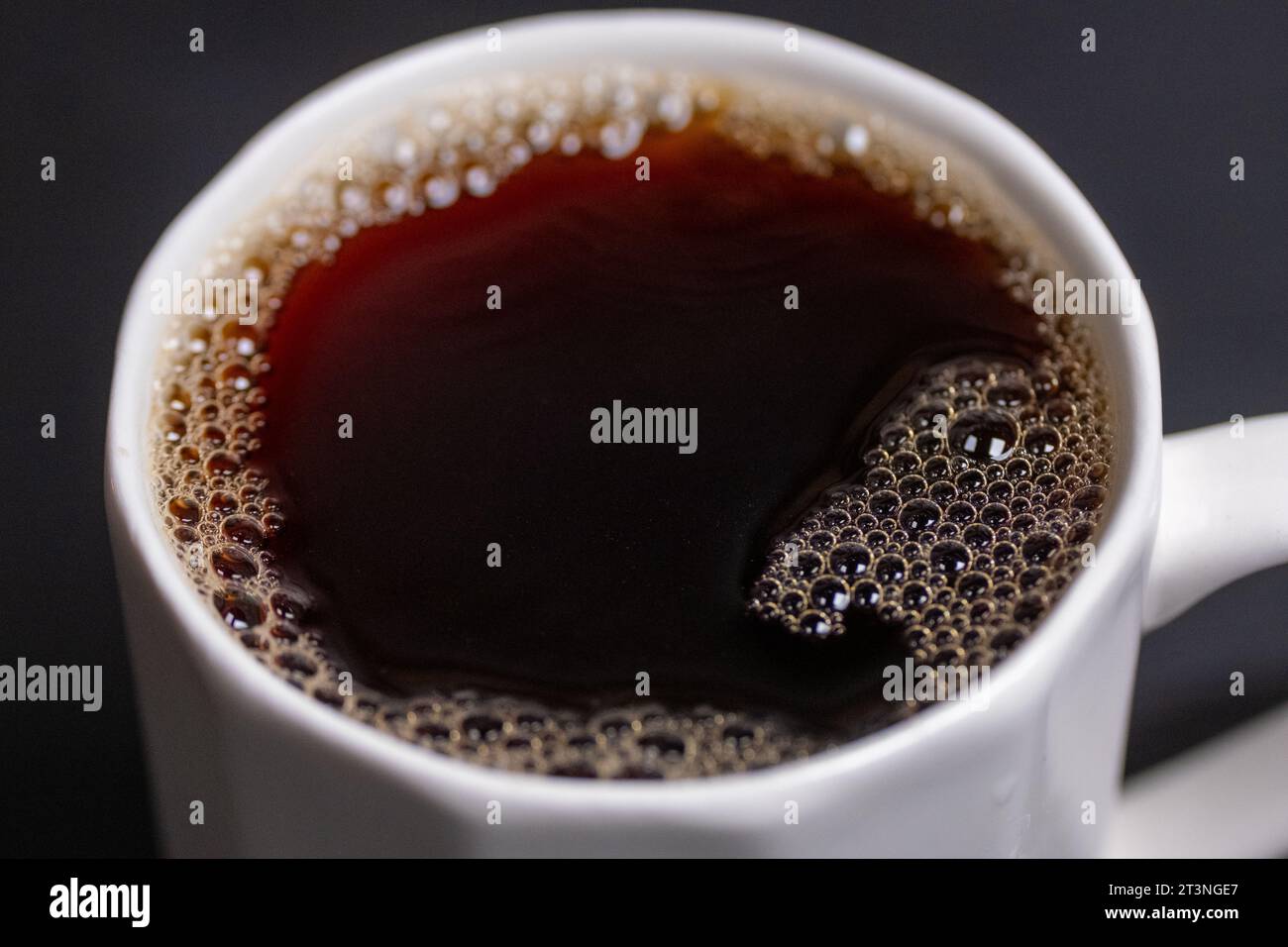 versare il caffè in un bicchiere in un espresso macro Foto Stock