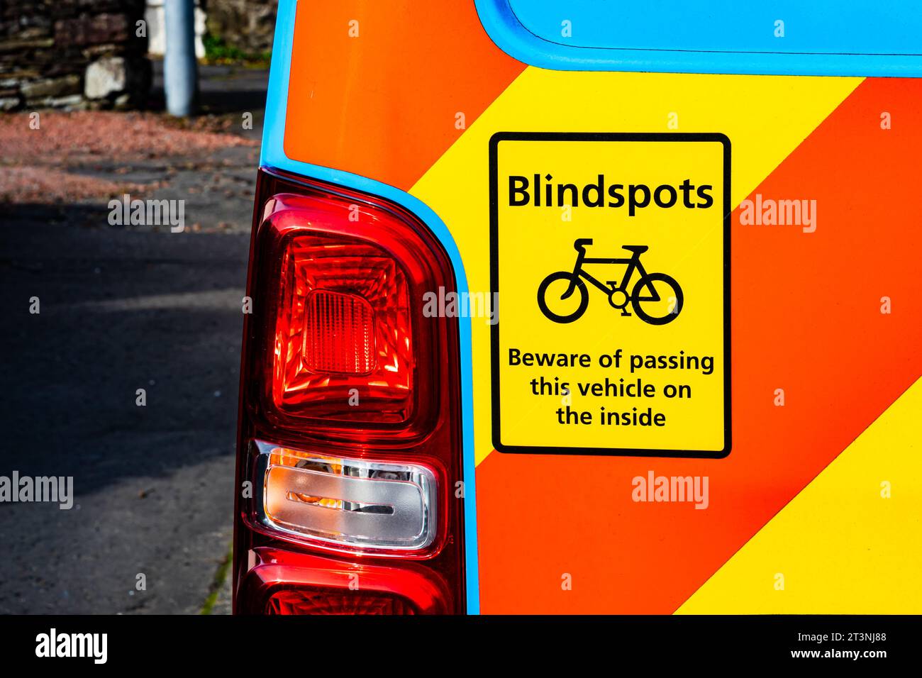 Furgone blu con contrassegni di avvertenza rossi e gialli con un adesivo di segnalazione dei punti ciechi dei ciclisti sul lato sinistro vicino al faro posteriore Foto Stock