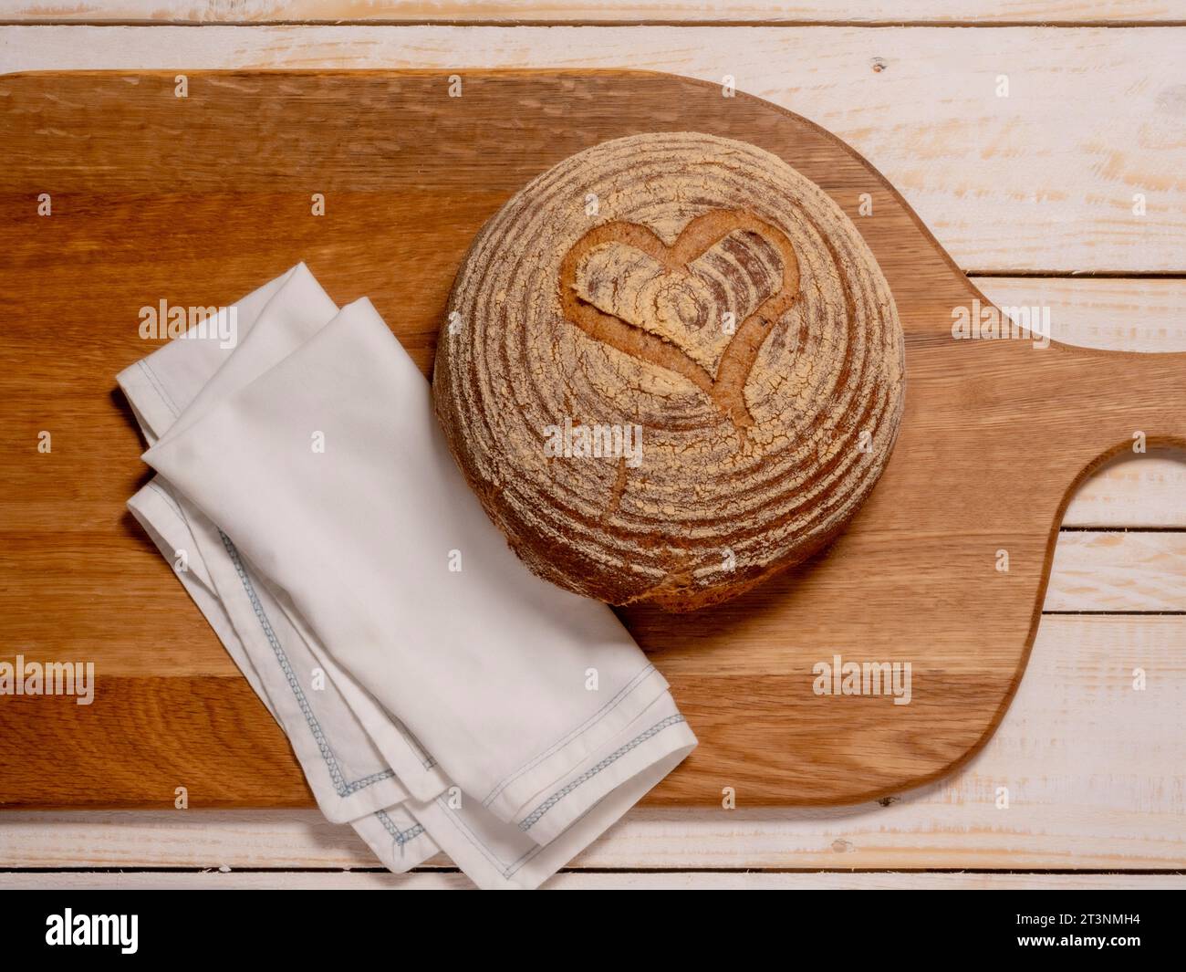 Piatto di un boule di pasta madre senza glutine, a forma di cuore, posizionato su una breadboard di legno. Foto Stock