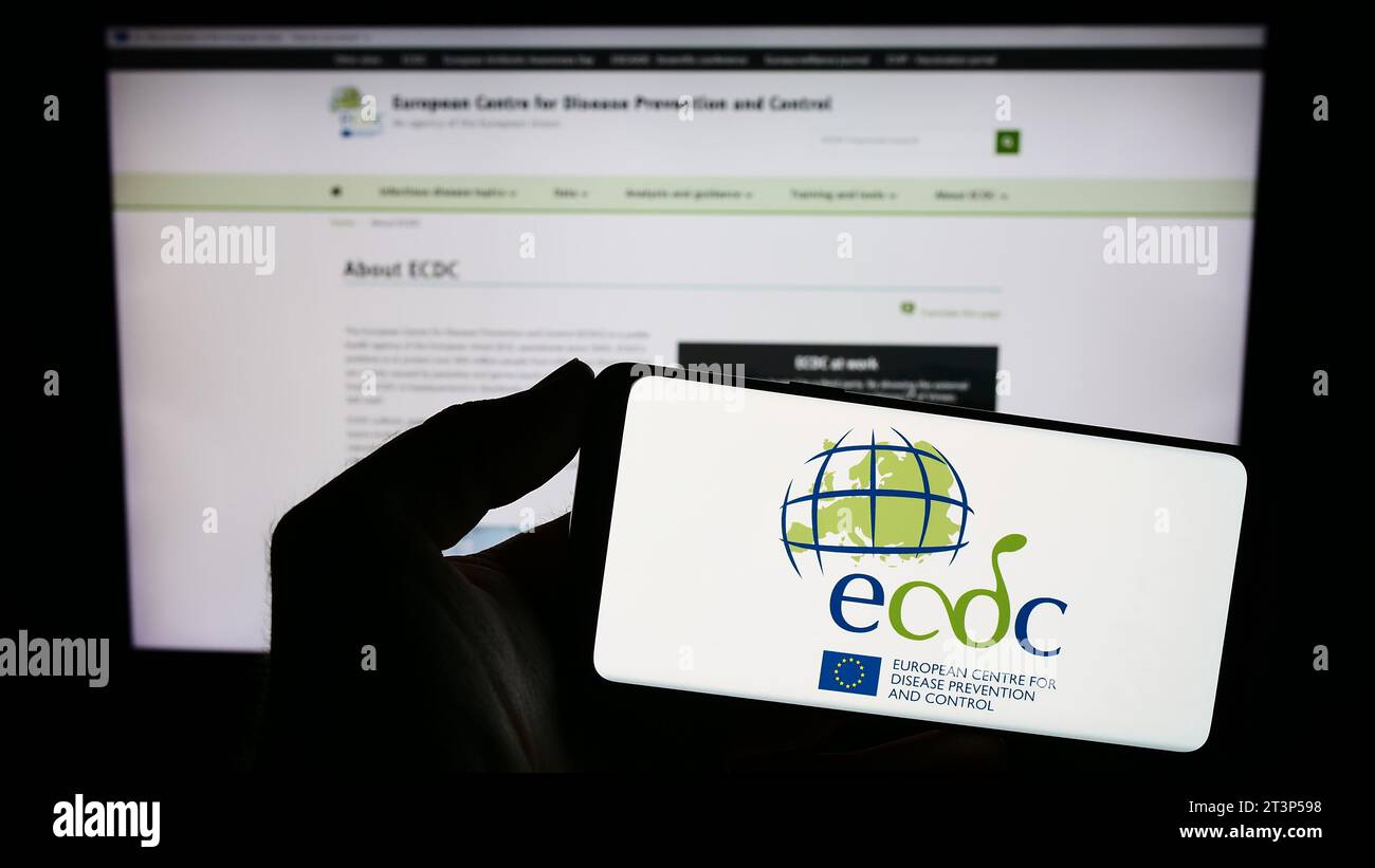 Persona che possiede uno smartphone con il logo del Centro europeo per la prevenzione e il controllo delle malattie (ECDC) davanti al sito web. Concentrarsi sul display del telefono. Foto Stock