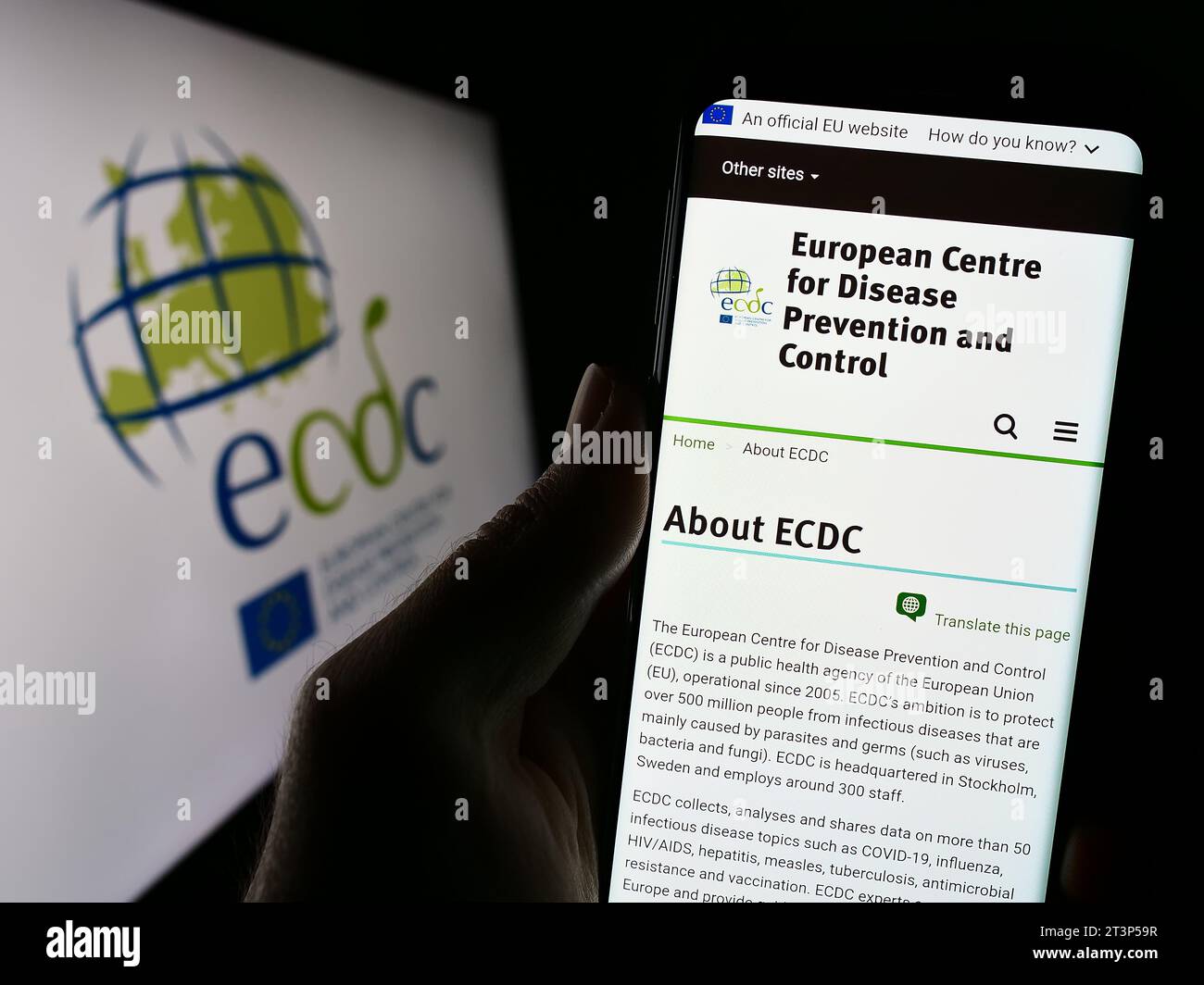 Persona in possesso di smartphone con sito web del Centro europeo per la prevenzione e il controllo delle malattie (ECDC) con logo. Concentrarsi sul centro del display del telefono. Foto Stock