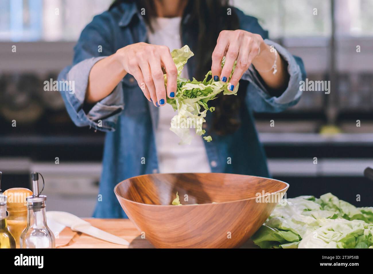 Una donna che prepara un'insalata verde nella sua cucina. Foto Stock