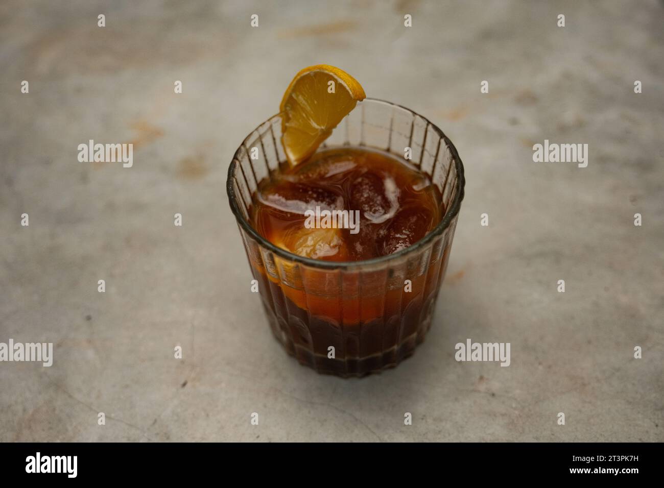 Viziatevi con la raffinatezza di un espresso Tonic adornato con una fetta di limone, elegantemente collocato su un tavolo di marmo. Foto Stock