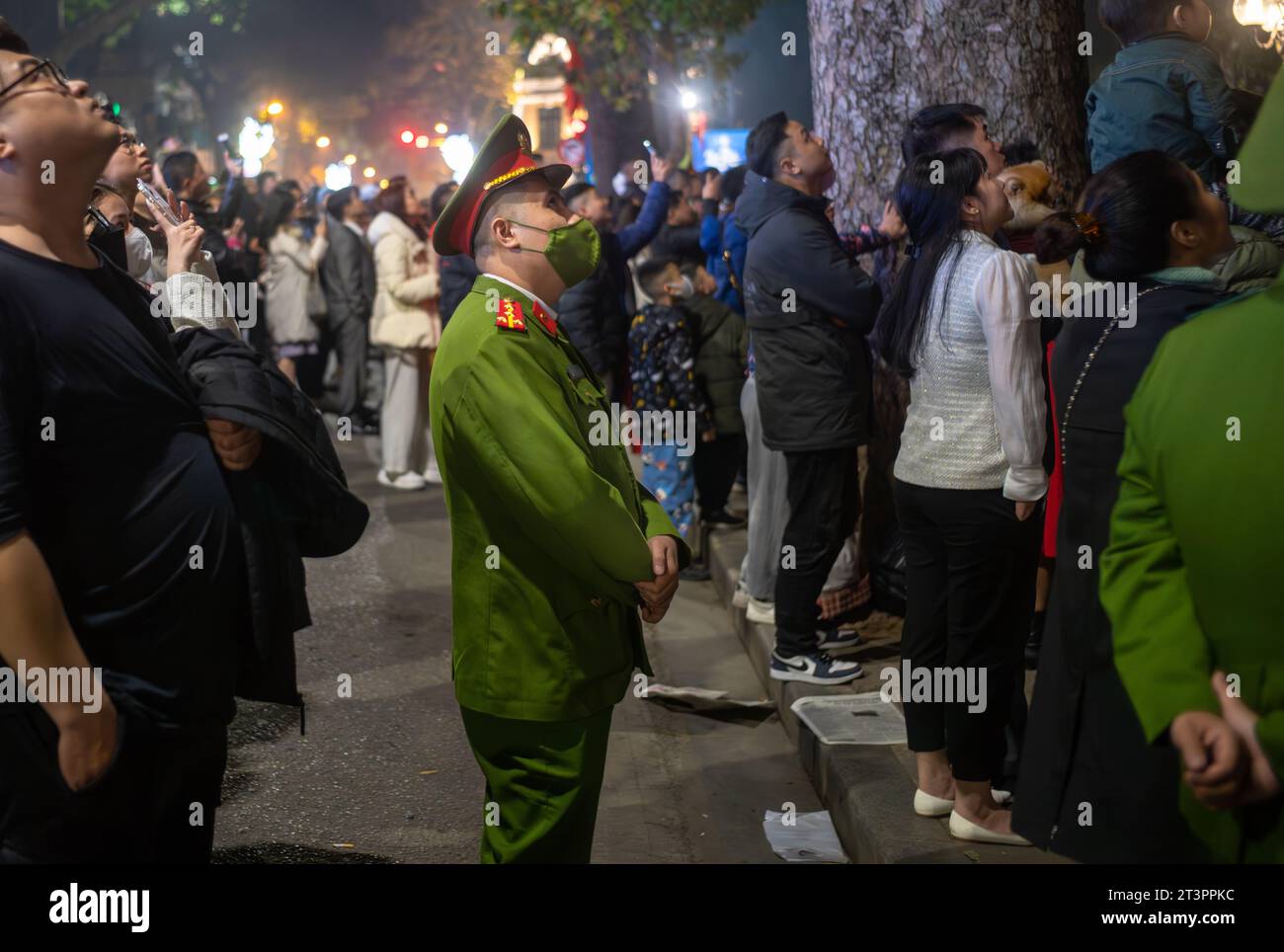 Un poliziotto vietnamita in uniforme e indossa una maschera facciale si trova in una folla per guardare i fuochi d'artificio al Tet, o Capodanno lunare, ad Hanoi, in Vietnam. Foto Stock