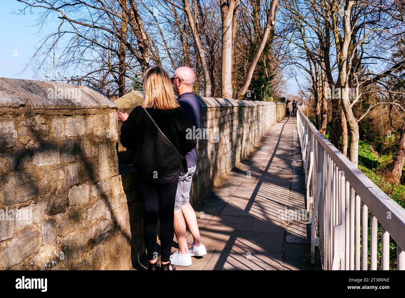 Gente che cammina lungo il muro. York, fin dai tempi dei romani, è stata difesa da mura. Ad oggi, parti sostanziali delle mura rimangono, e York ha m Foto Stock