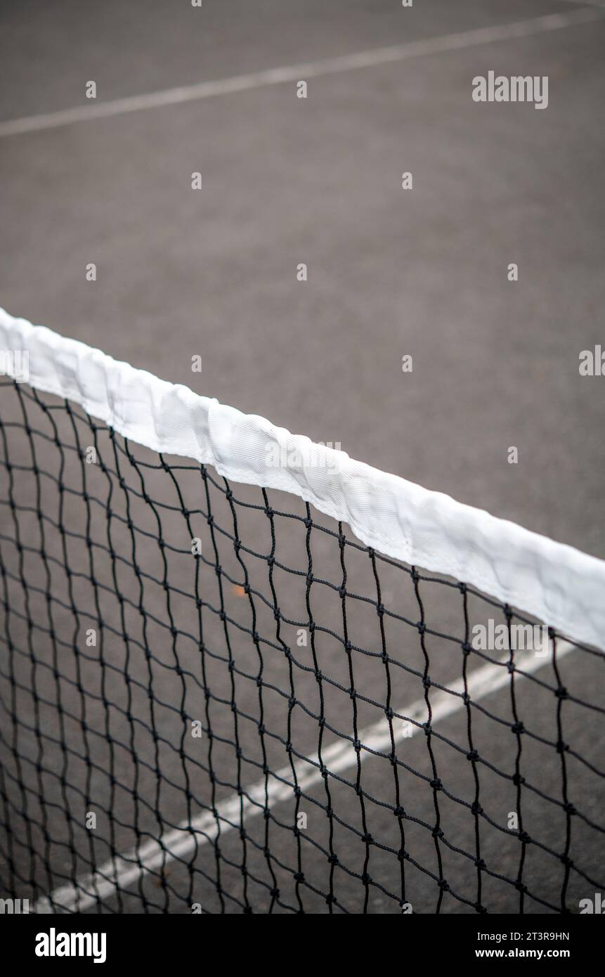 Dettaglio della parte superiore di una rete da tennis su un campo esterno in cemento Foto Stock