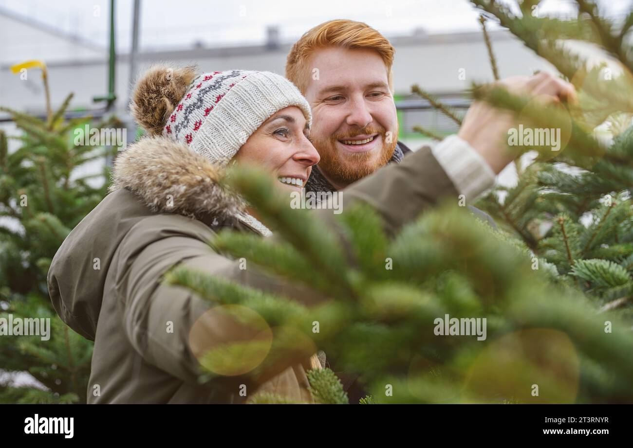 Coppia felice che sceglie l'albero di Natale alla fiera X-mas Foto Stock