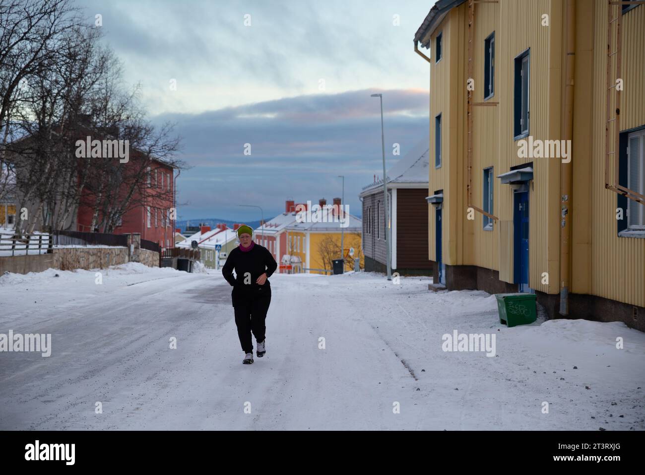 Kiruna, Swenden- 29 novembre 2022: Una vecchia donna bianca che fa jogging in Winter Street Foto Stock