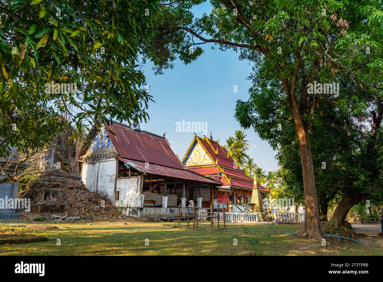 Piccolo tempio buddista sull'isola di Don Khone. Splendidi edifici antichi, nel tardo pomeriggio, circondati da molti alberi frondosi, che donano ombra in un tranquillo su Foto Stock