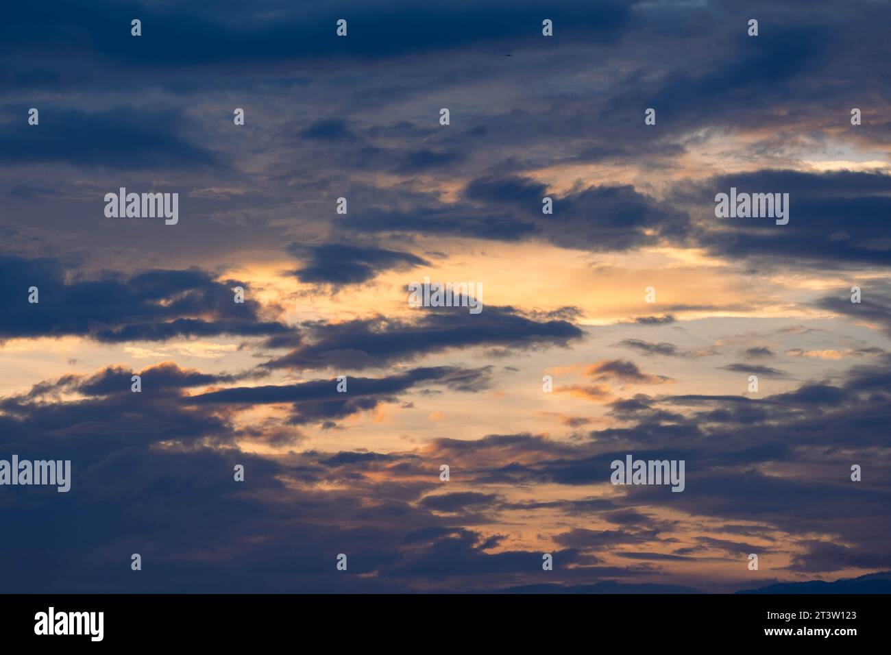 Cielo tramonto con raggi dorati del sole sullo sfondo di sagome di paesaggi montani e villaggi rurali. Vista aerea del bel cielo w Foto Stock