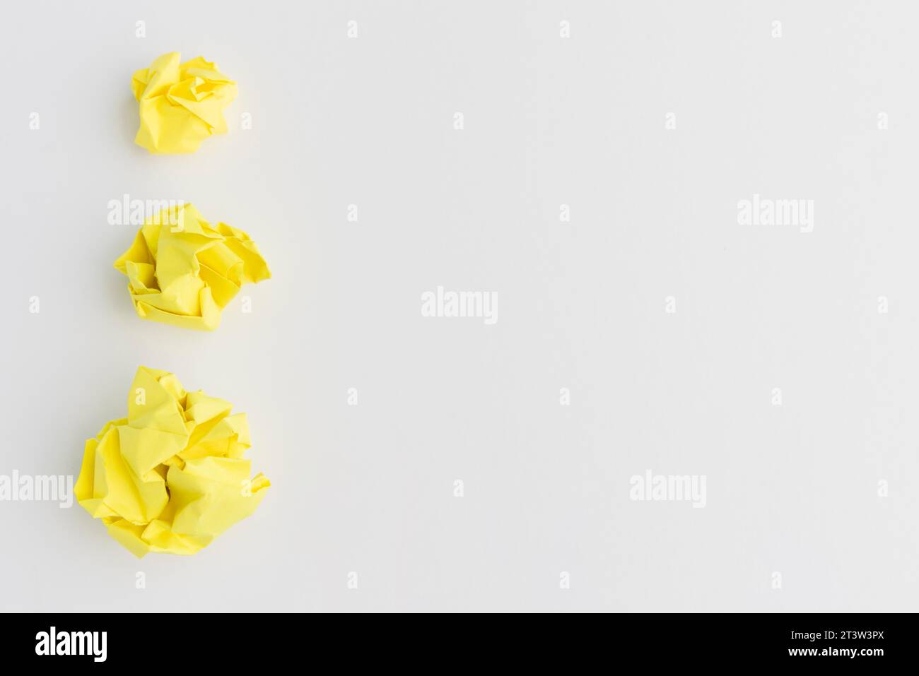 Tre palline di carta spaccate gialle di diverse dimensioni su sfondo bianco Foto Stock