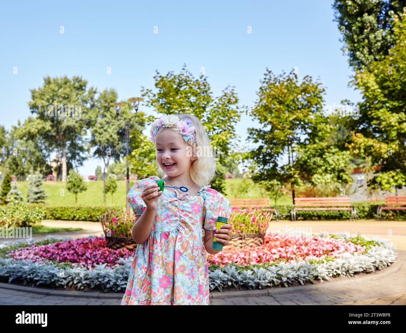 Una bambina che soffia bolle di sapone nel parco estivo. Concetto di estate, infanzia e tempo libero Foto Stock