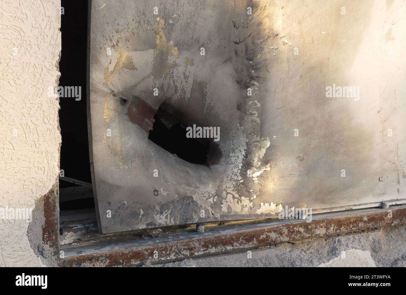 Una finestra resistente agli urti e alle schegge di una stanza sicura mostra i danni di un GDR con granata a razzo durante l'attacco del 7 ottobre da parte di militanti palestinesi di Hamas a Kibbutz Holit vicino al confine con Gaza il 26 ottobre 2023 a Holit, in Israele Foto Stock