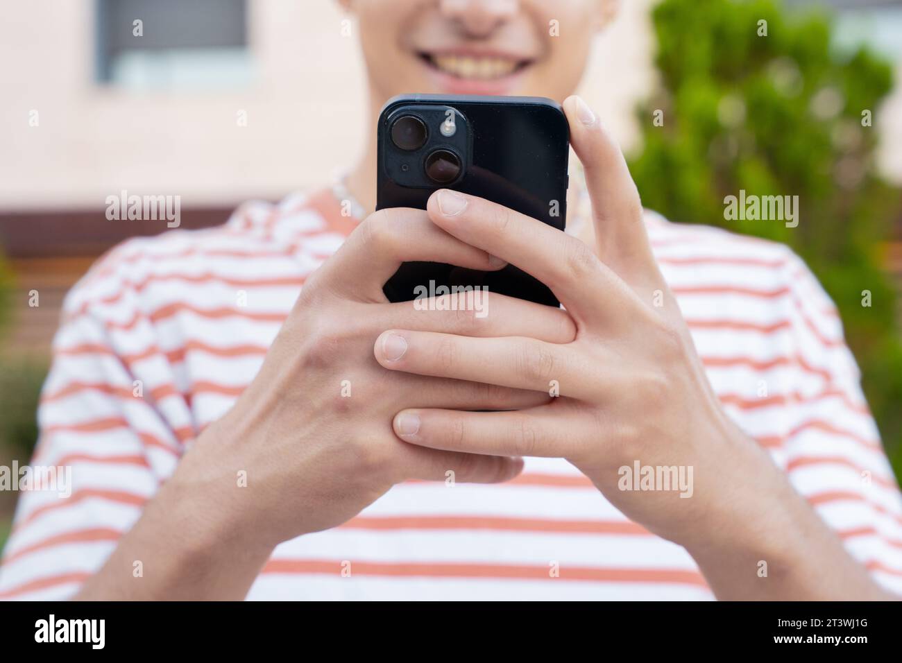 primo piano di un giovane sorridente che usa l'app per smartphone all'aperto. Foto Stock