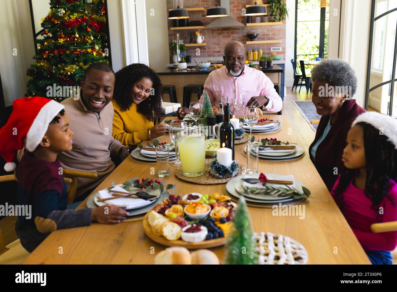 Felice famiglia afro-americana che cena di natale nella sala da pranzo decorata a casa Foto Stock