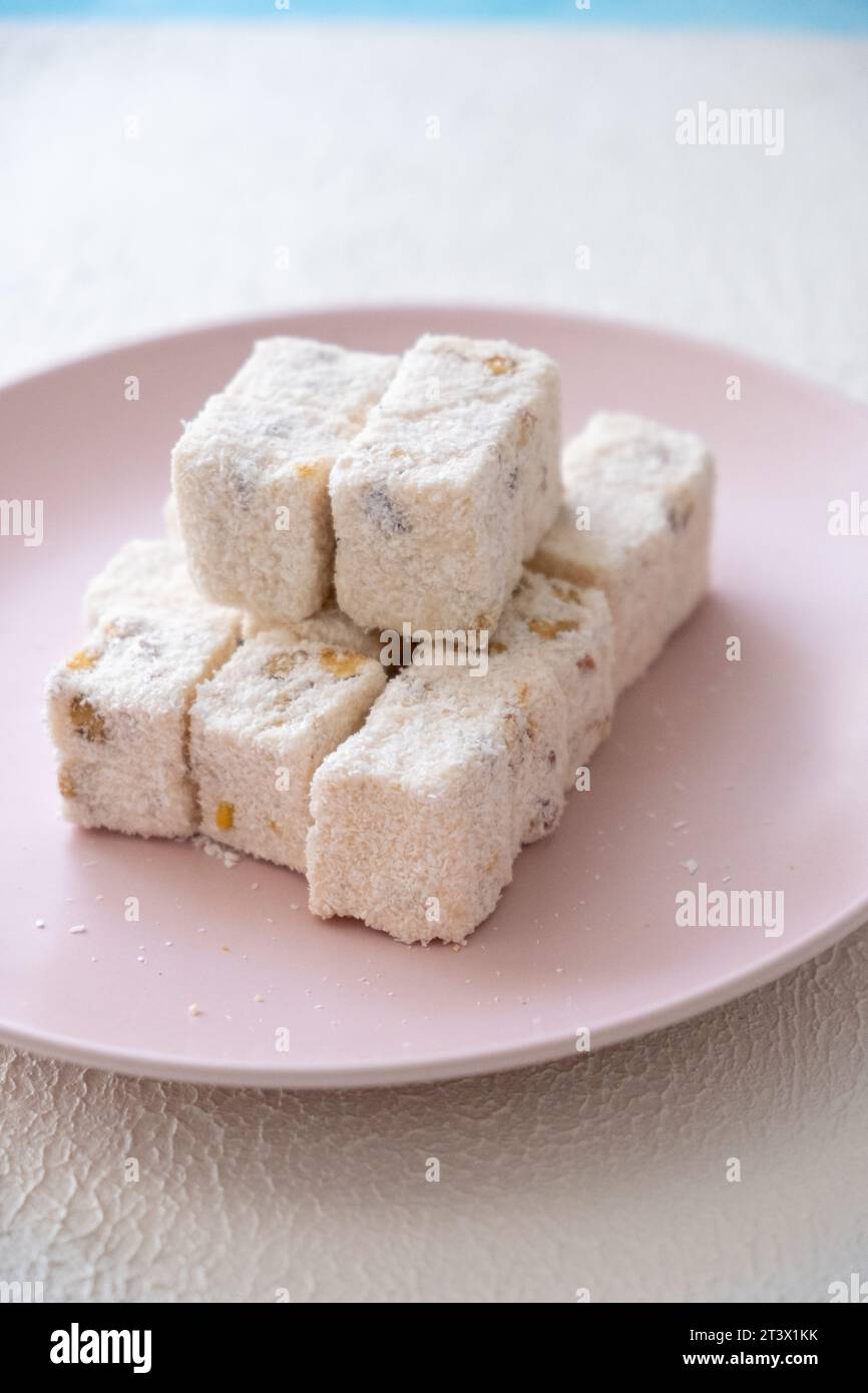 Delizie turche con nocciole, pistacchi, noci, cocco e rose su un piatto rosa Foto Stock