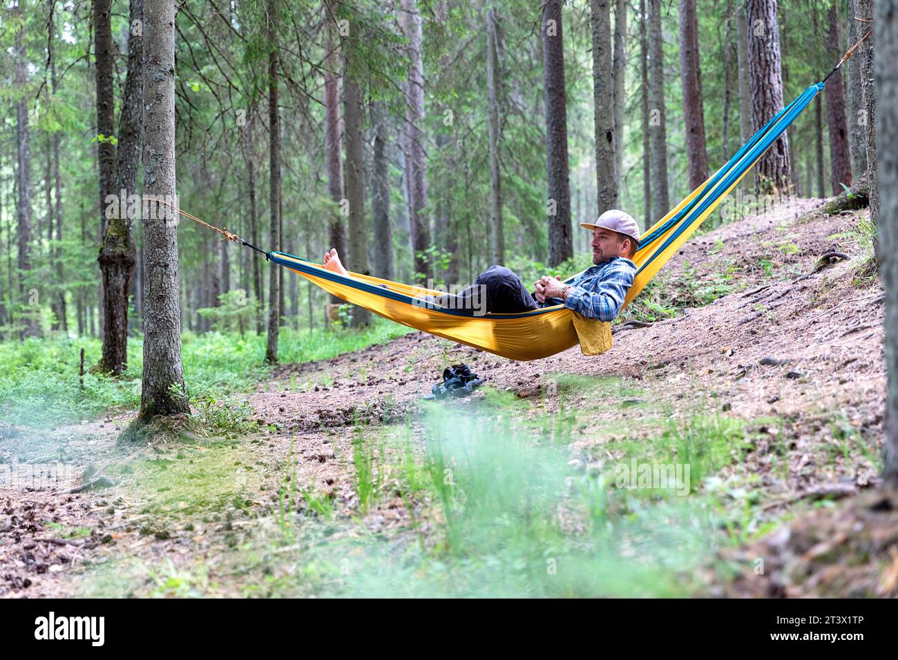 Un uomo, turista, che si rilassa in un'amaca in una foresta in Estonia, mentre fa escursioni e campeggi nella natura selvaggia estone, in Estonia, in Europa Foto Stock