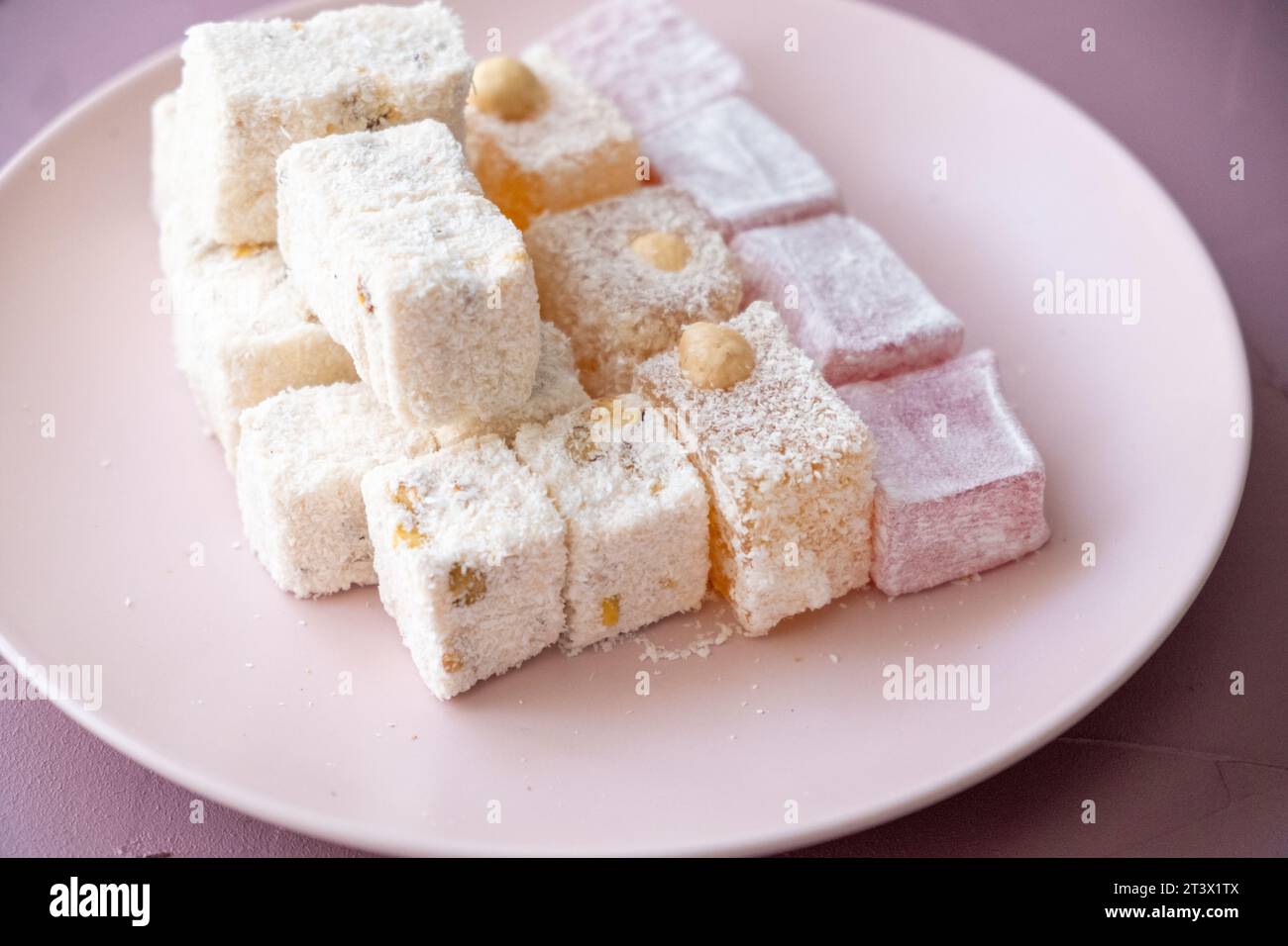 Delizie turche con nocciole, pistacchi, noci, cocco e rose su un piatto rosa Foto Stock