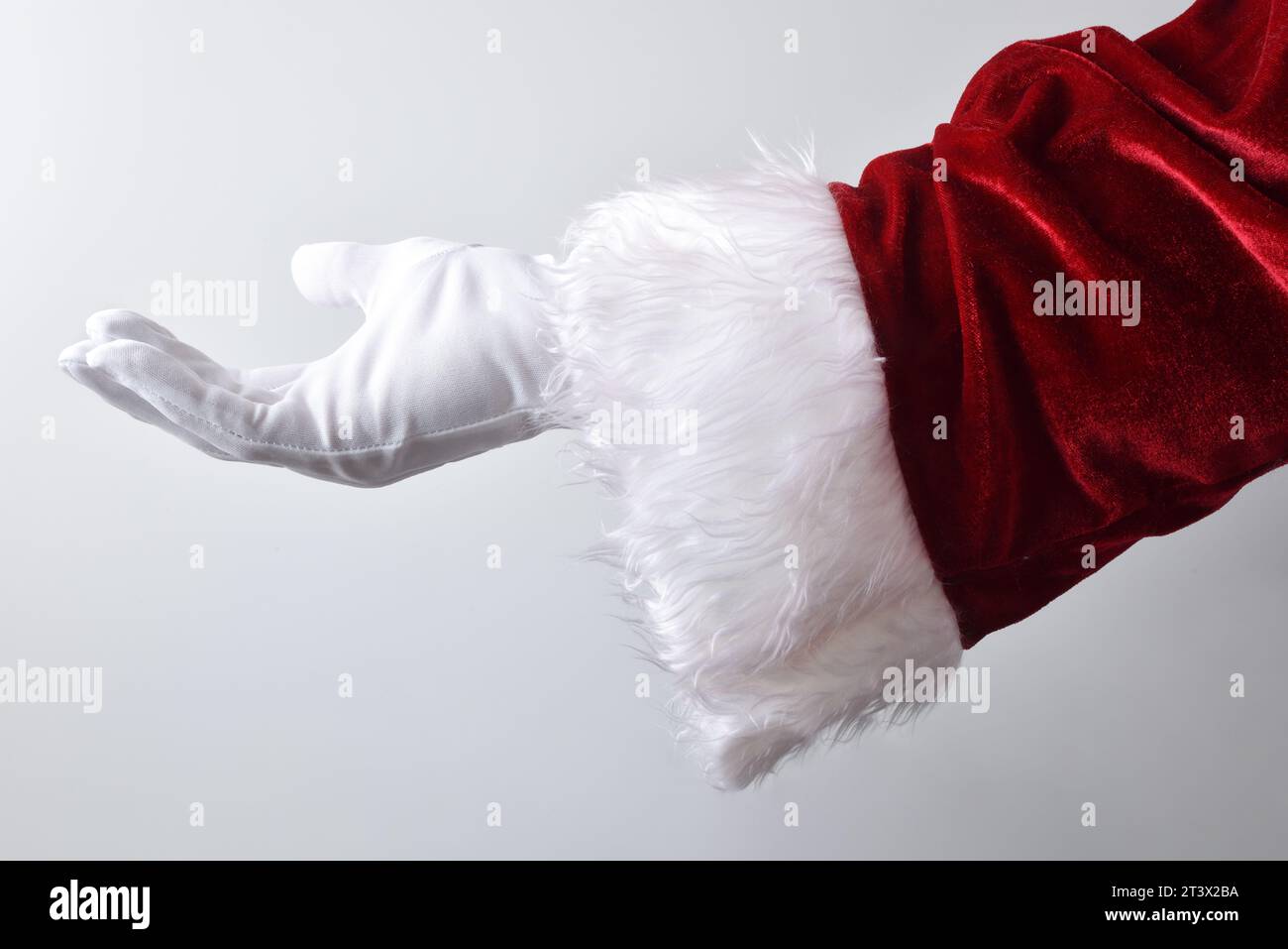 Mano di Babbo natale con guanto bianco e costume tradizionale rosso gesto che offre qualcosa con sfondo bianco sfumato. Foto Stock