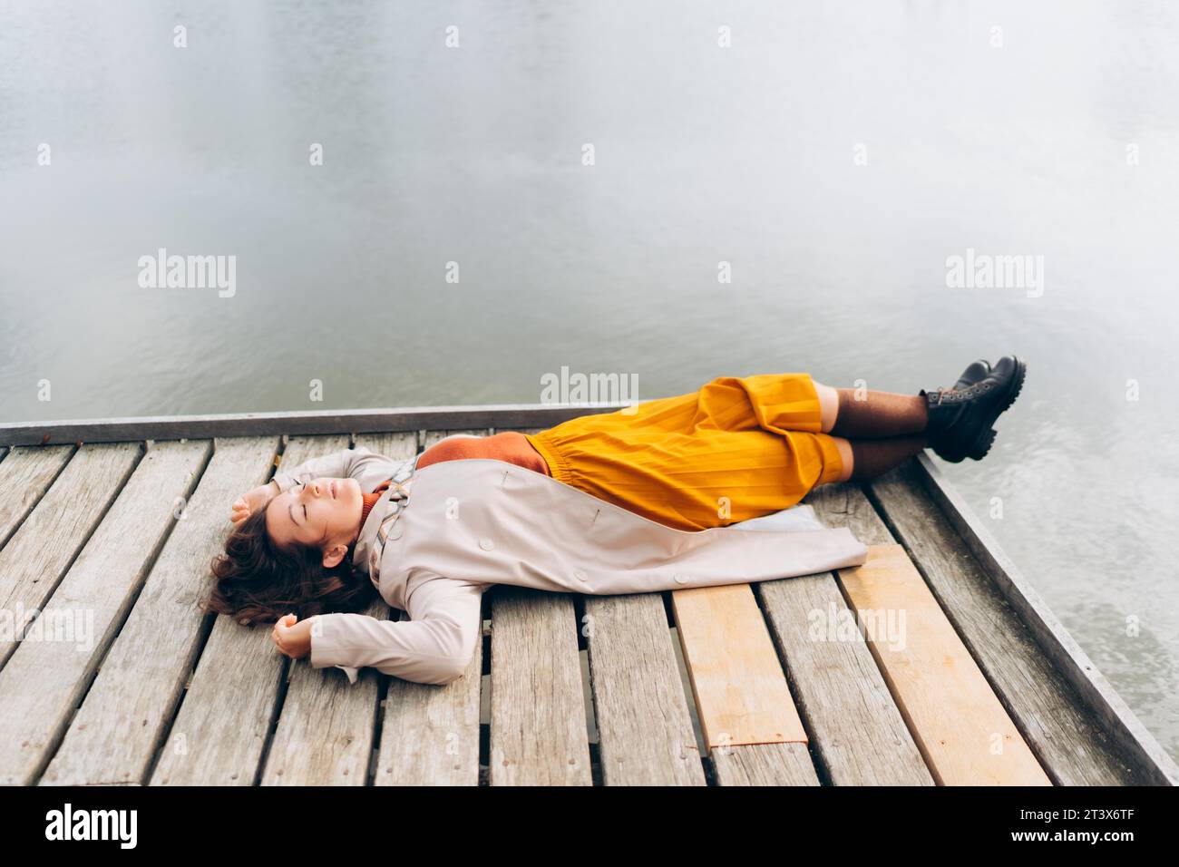 Giovane donna giace sulla riva di un lago, autunno soleggiato Foto Stock