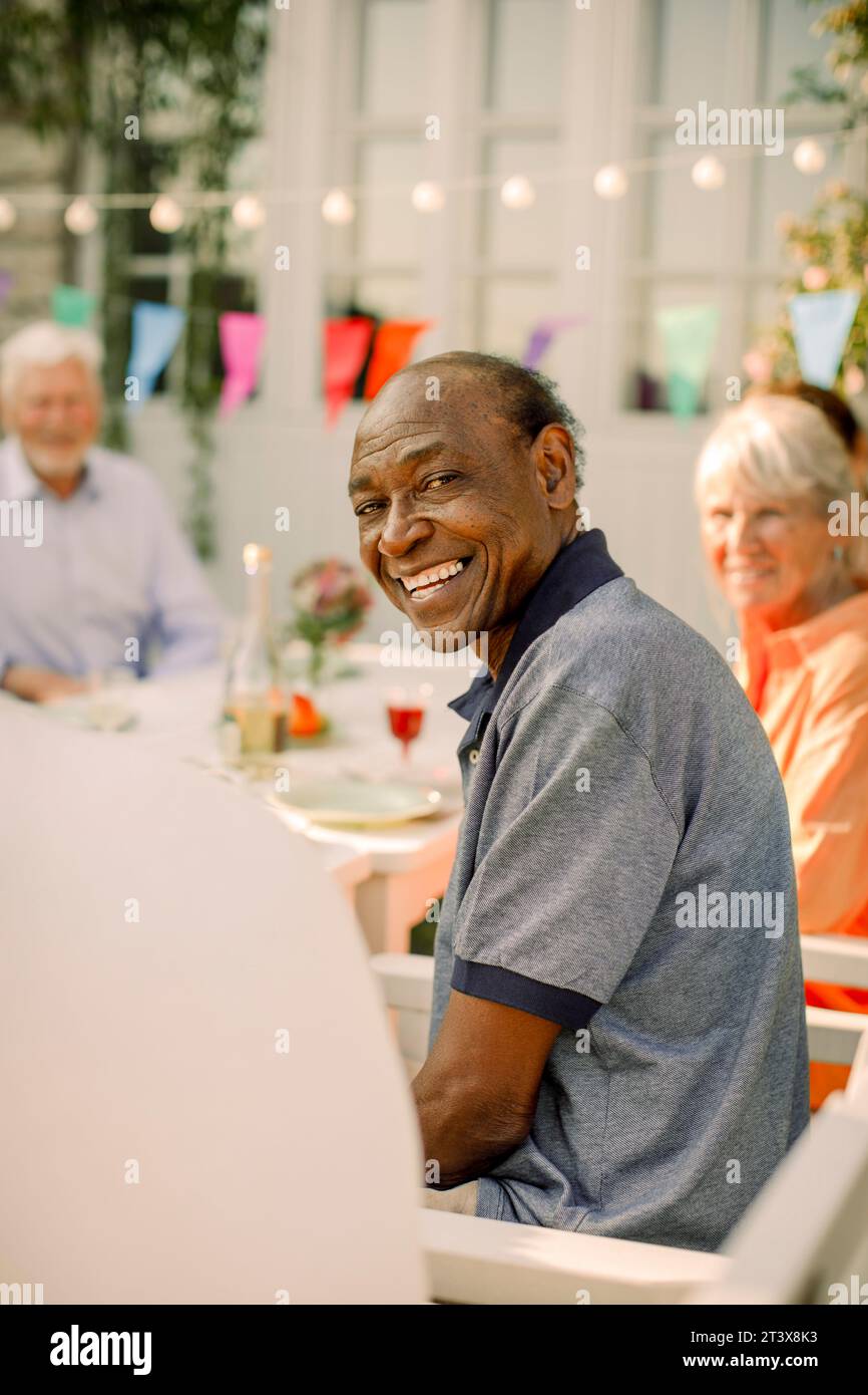 Ritratto di un anziano sorridente seduto sul cortile posteriore Foto Stock