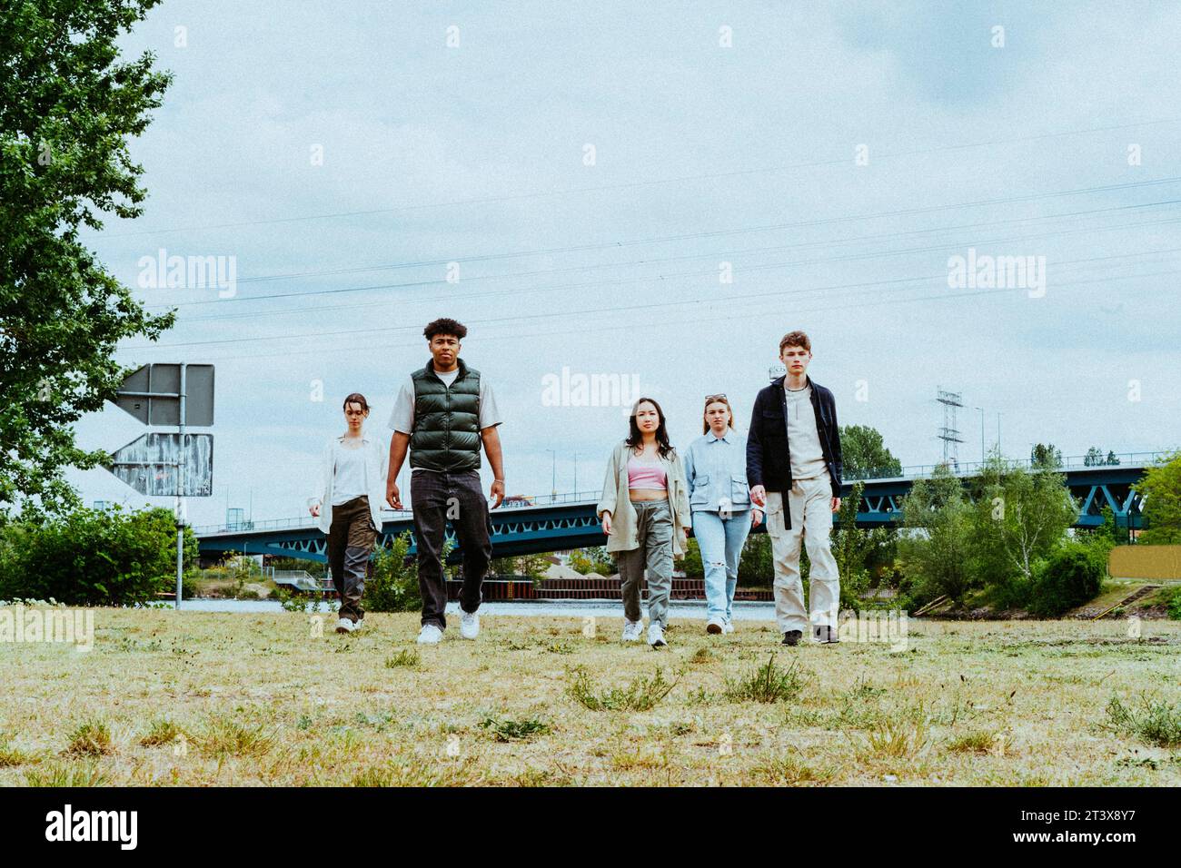 Ritratto completo di giovani amici che camminano verso il fiume contro il cielo Foto Stock