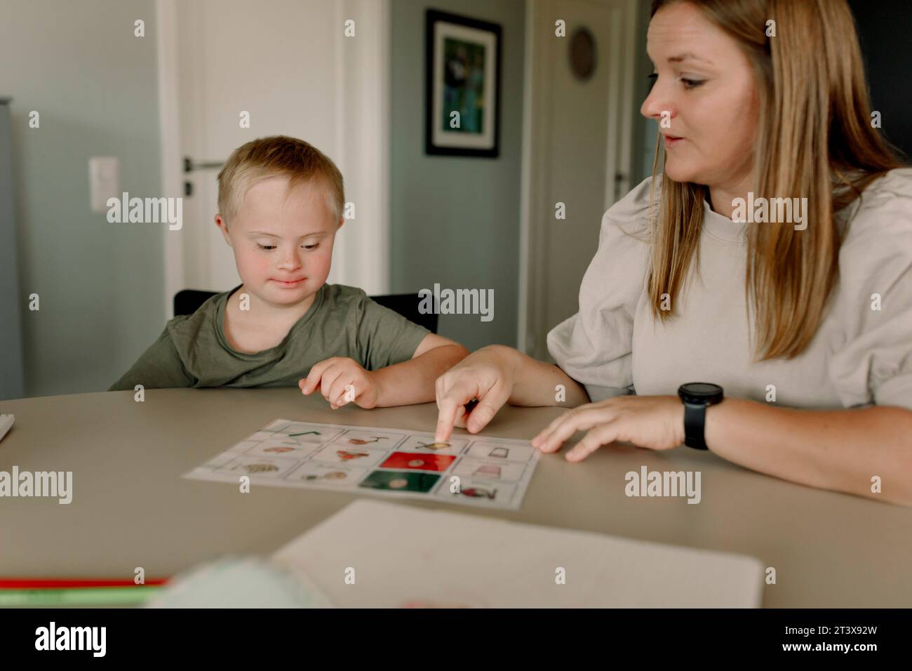 Madre che insegna al figlio con la sindrome di Down a casa Foto Stock