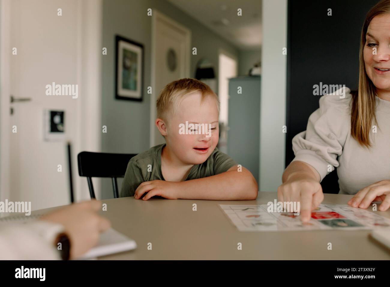 Madre che insegna a un ragazzo con la sindrome di Down a casa Foto Stock
