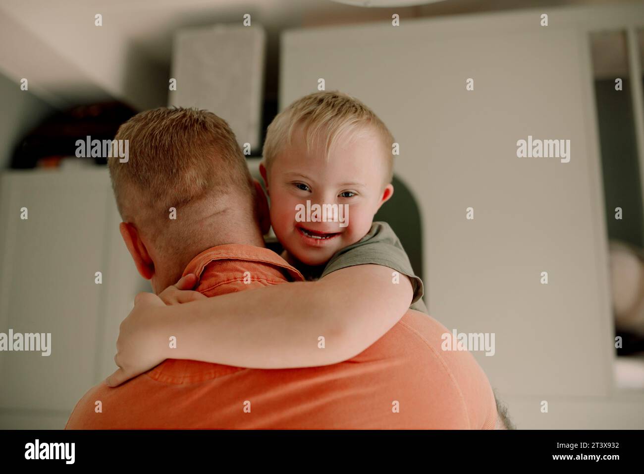 Ritratto di un ragazzo con sindrome di Down che abbraccia il padre a casa Foto Stock