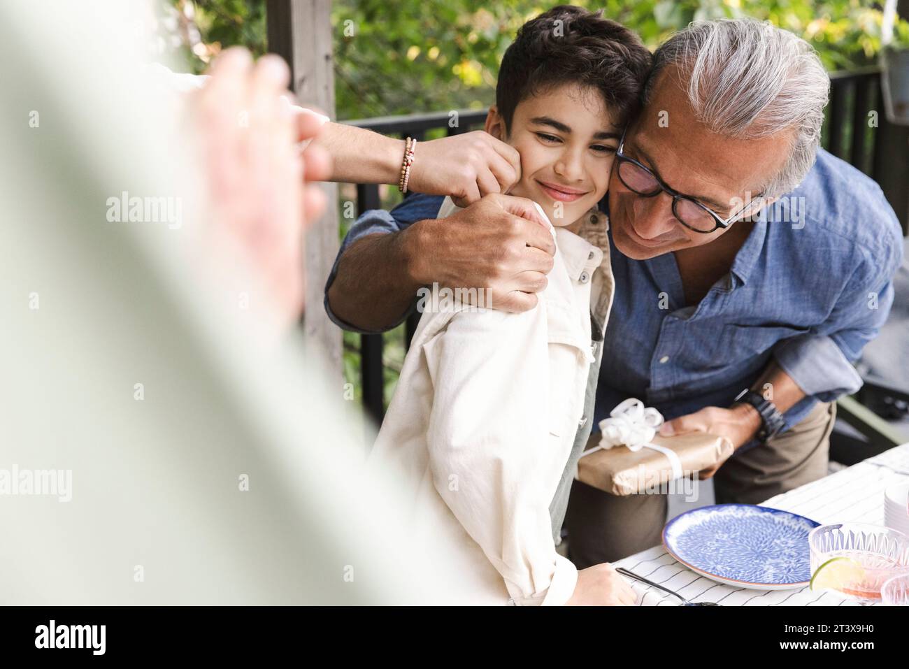 Uomo anziano che abbraccia il nipote durante la cena di mezza estate Foto Stock