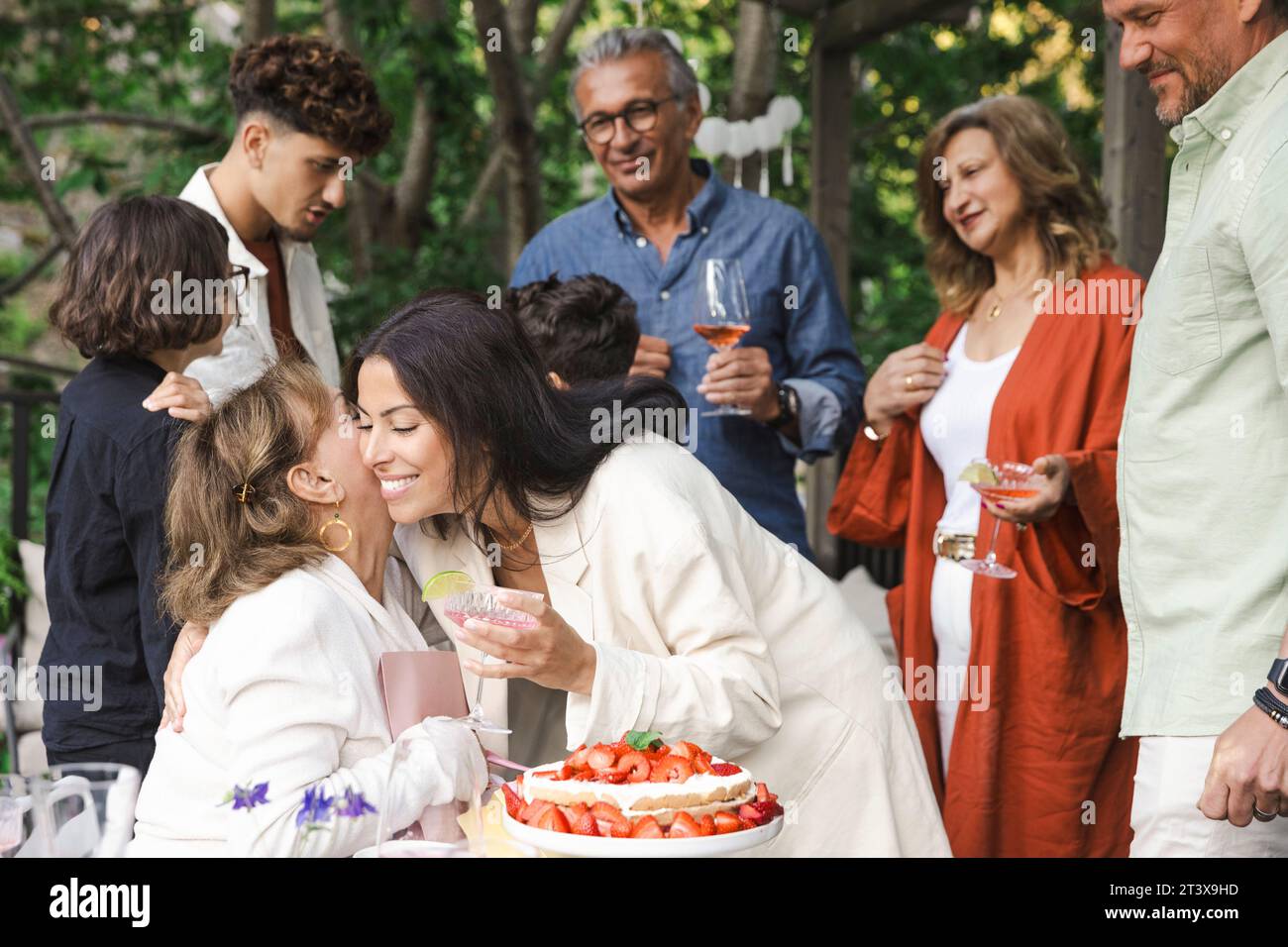 Donne felici che si abbracciano durante la cena di mezza estate Foto Stock