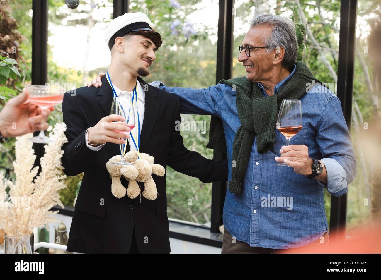 Uomini sorridenti con le braccia l'uno intorno all'altro alla festa estiva Foto Stock